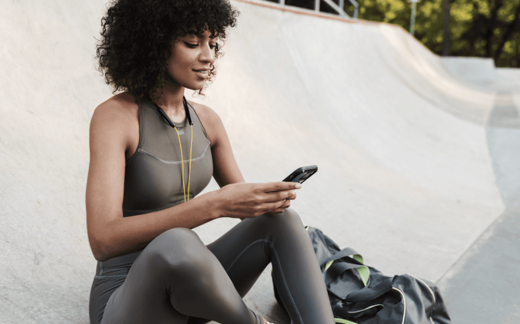 Mulher sorrindo com um celular e um cartão de crédito na mão